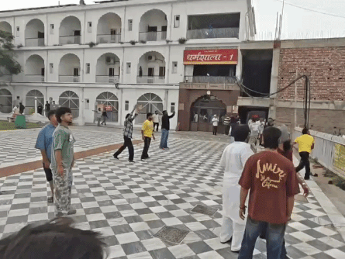 मंदिर में एक युवक (रेलिंग के पास पीली टी-शर्ट में) पत्थर फेंकता हुआ दिखा।