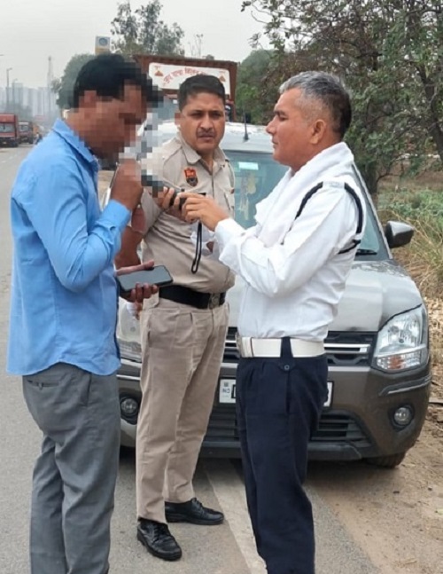 मशीन लगाकर वाहन चालक की जांच करते पुलिसकर्मी।