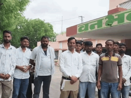 कार्यालय के बाहर प्रदर्शन करते लोग।