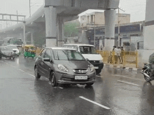 फरीदाबाद में बारिश के बीच गुजरते वाहन।