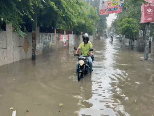 रोहतक के मॉडल टाउन में जलभराव के बीच युवक की बाइक बंद हो गई। इसी जलभराव के बीच होकर जाते बाइक और स्कूटी सवार।