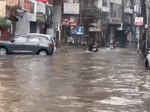 मॉडल टाउन में पानी से गुजरते लोग।