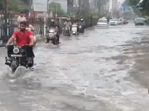 दिल्ली रोड पर भरे पानी से गुजरते लोग।