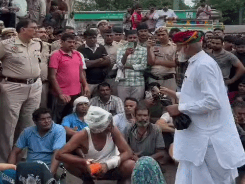 गुरुग्राम में युवक की हत्या के बाद सड़क जाम करके बैठे ग्रामीण पुलिस अधिकारियों से सवाल पूछते हुए।