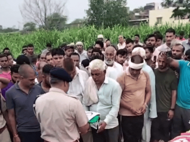 अधिकारी लोकेश के पिता को तिरंगा झंडा सौंपते हुए।