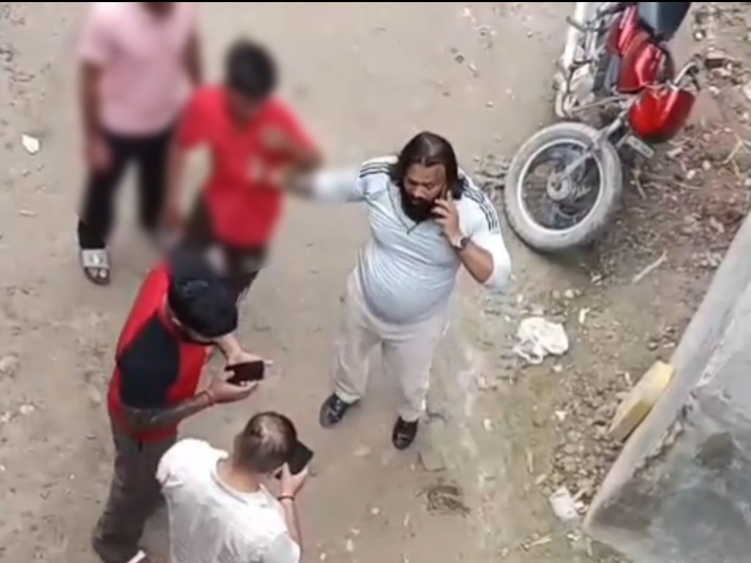 फरीदाबाद में नाबालिग लड़के को पकड़े खड़ा युवक।