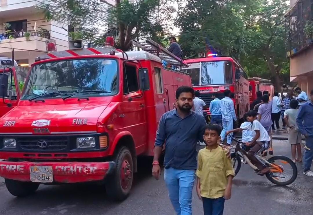 अपार्टमेंट के बाहर खड़े स्थानीय निवासी और फायर ब्रिगेड की गाड़ियां