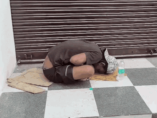 नशे में युवक सिर जमीन पर टिकाकर बैठा।