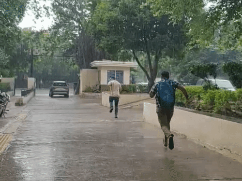 फरीदाबाद में दोपहर में हुई बारिश से बचने के लिए भागकर जाते युवक।