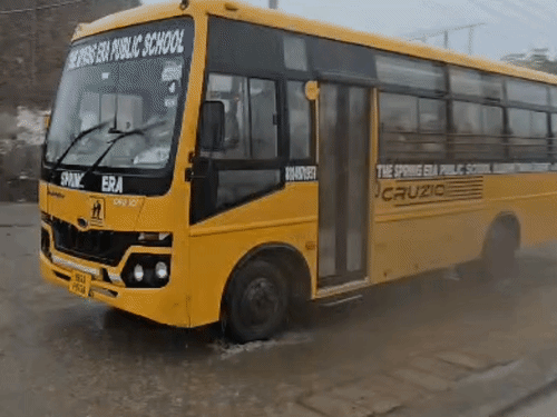 सोनीपत में तेज बारिश में जलभराव के बीच से गुजरती स्कूली बस।