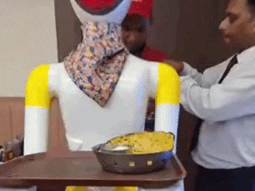 Dhaba staff placing food on a plate fixed on the robot's hands.