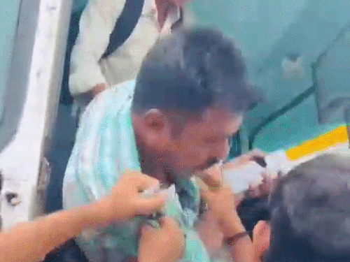 आरोपी की गर्दन पकड़कर उसे बस से नीचे उतारती सवारी।