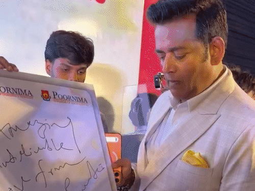 Actor Ravi Kishan signing autographs and writing his experiences during the event.