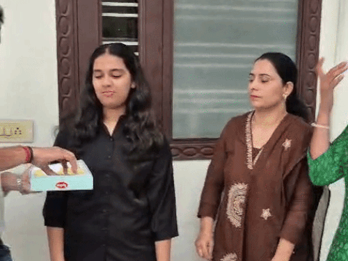 बेटी का नाशा में चयन होने पर मिठाई खिलाता पिता।