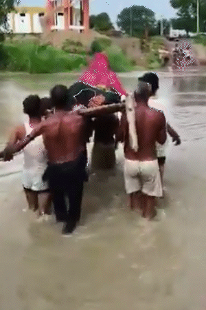 उत्तर प्रदेश के चित्रकूट में गर्भवती महिला को चारपाई पर लिटाकर लोगों ने नाला पार कराया।