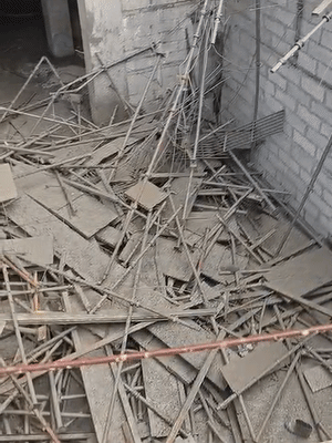 शटरिंग गिरने के बाद जमीन पर बिखरे लोहे की पाइपें और अन्य सामान।