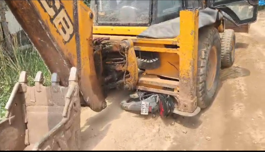 जेसीबी के नीचे पड़ी बाइक