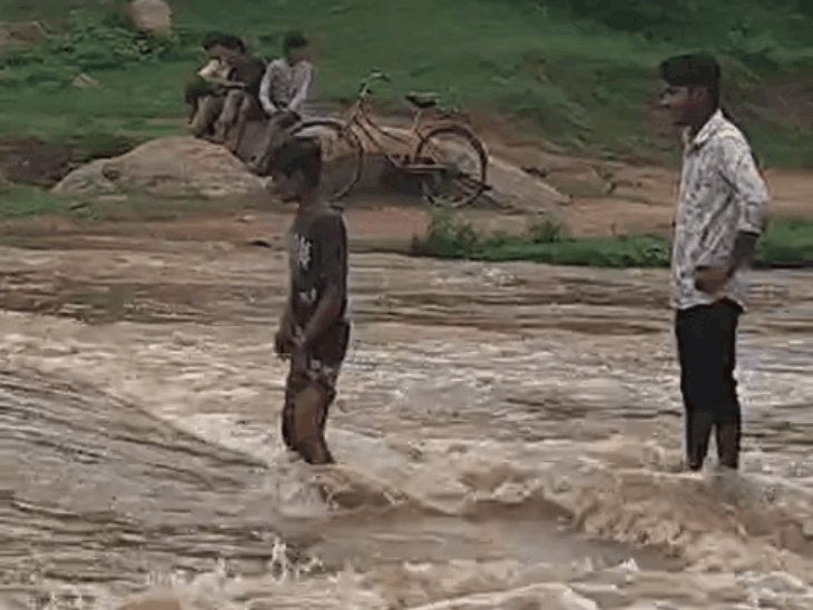 ग्रामीण बच्चों को कंधे पर बैठाकर कुम्हेड़ नदी पार कराते हैं।