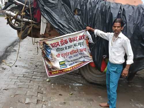 युवकों की ट्रैक्टर-ट्रॉली पर लगा डाक कांवड़ यात्रा का पोस्टर।