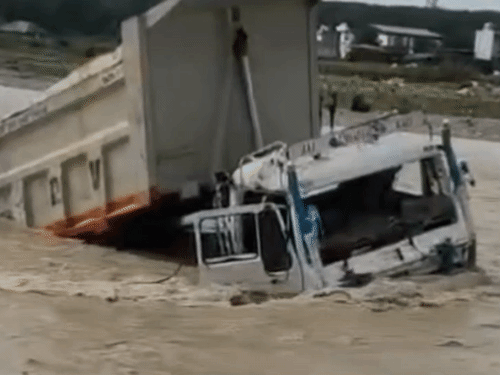 A truck dumper got stuck in the sudden flood in Tons river in Jhajhra, Dehradun on Sunday. However, people including the driver came out safely in time.