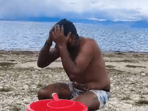 मानसरोवर झील के किनारे स्नान करता व्यक्ति।