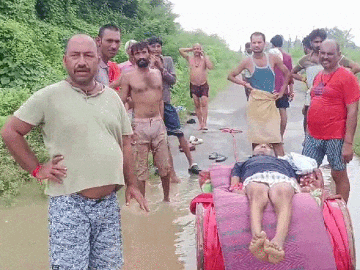 शव को पानी भरा रास्ता पार कराने के बाद खड़े ग्रामीण।