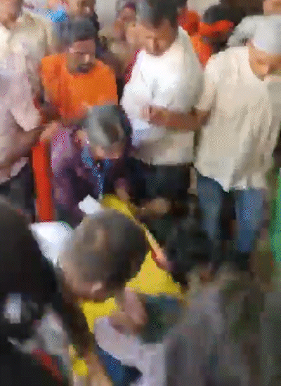 चेंगराचेंगरीत पडलेल्या एका महिला भाविकाला उचलणारे लोक.