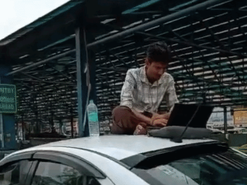 हरियाणा में गुरुग्राम में सोहना रोड पर जलभराव के चलते एक युवक कैब की छत पर बैठकर लैपटॉप खोलकर काम करने लगा।