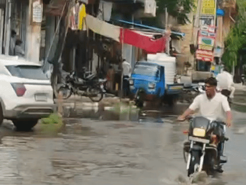 नूंह में गोशाला रोड पर जलभराव से गुजरता बाइक सवार।