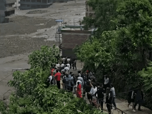 रसुवा जिले में पानी का बहाव थमने के बाद टूटे मकान और मलबे में दबी गाड़ियां दिखीं।