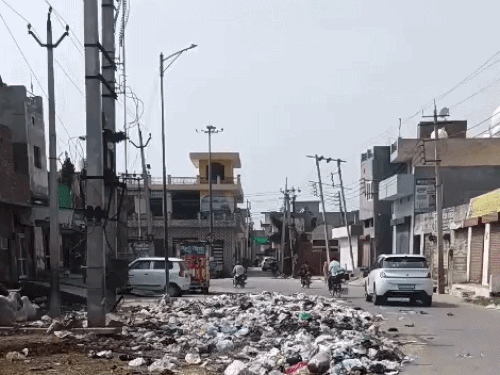 डोगरा गेट पर कचरे के ढेर के पास से गुजरते वाहन।
