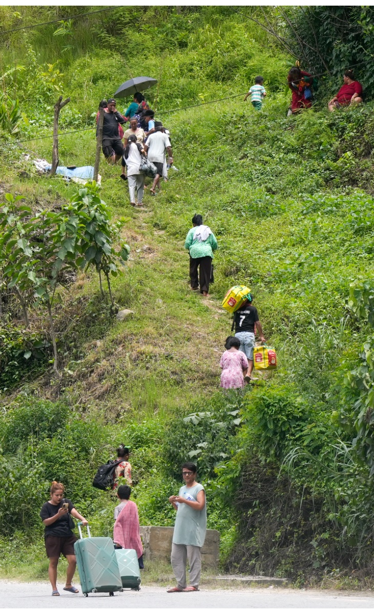 बाढ़ की चेतावनी जारी होने के बाद लोग सुरक्षित जगहों की ओर जाते हुए।