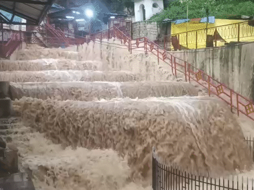 घाट की ओर जाने वाली सीढ़ियों पर झरने की तरह पानी बह रहा है।
