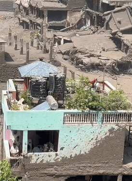 मलबा और पानी शांत होने के बाद एक आदमी घर की छत पर टी-शर्ट लहराकर रेस्क्यू टीम को बुलाने की कोशिश कर रहा है।