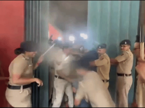 PU में लॉ डिपार्टमेंट के गेट पर पुलिस कर्मचारी एक छात्र को टांग से खींचता दिखा।