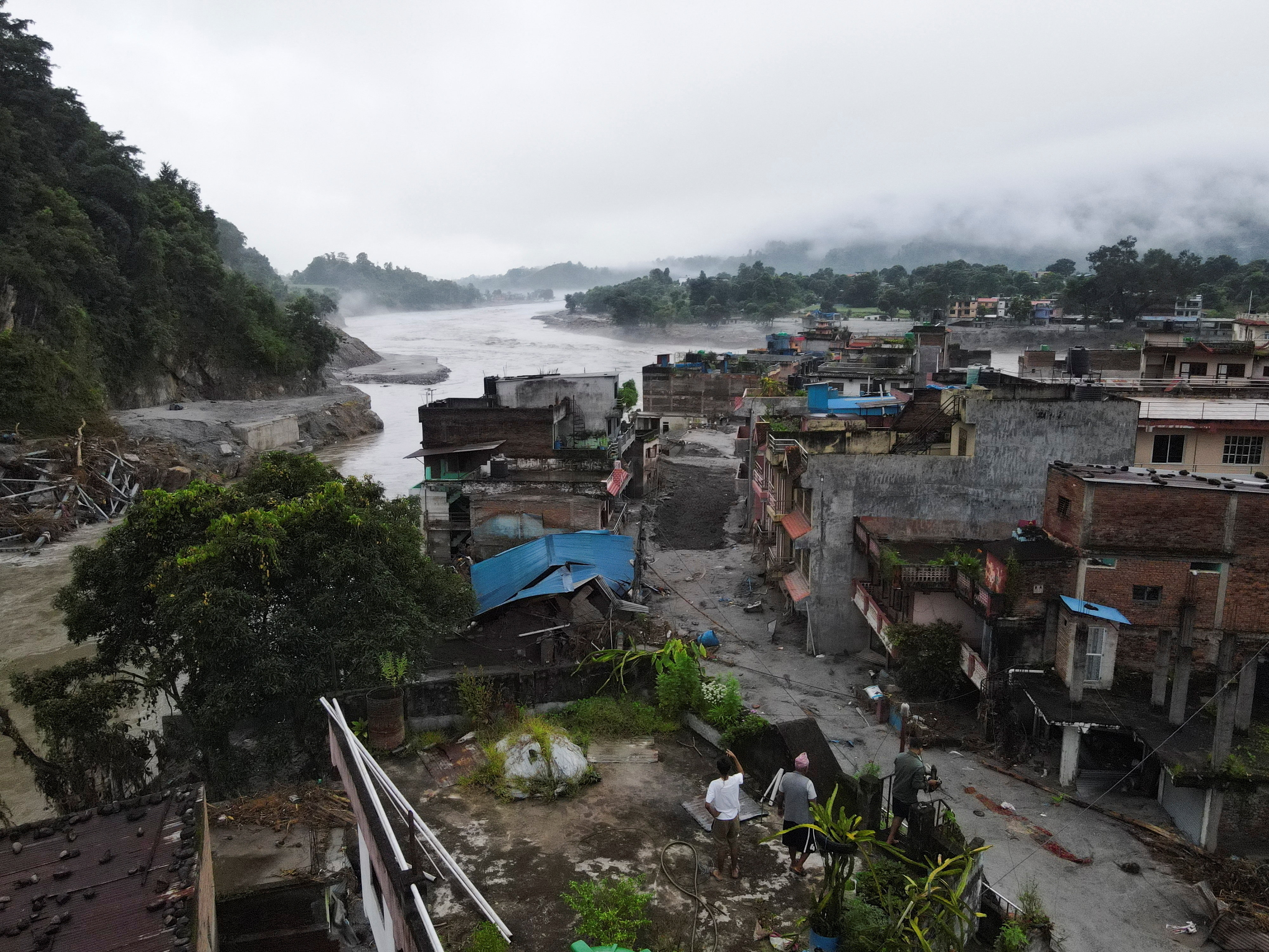 नेपाल के नुवाकोट जिले के देवीघाट में भीषण बाढ़ और भूस्खलन के बाद क्षतिग्रस्त मकान का जायजा लेते लोग। तस्वीर 31 अगस्त की है।