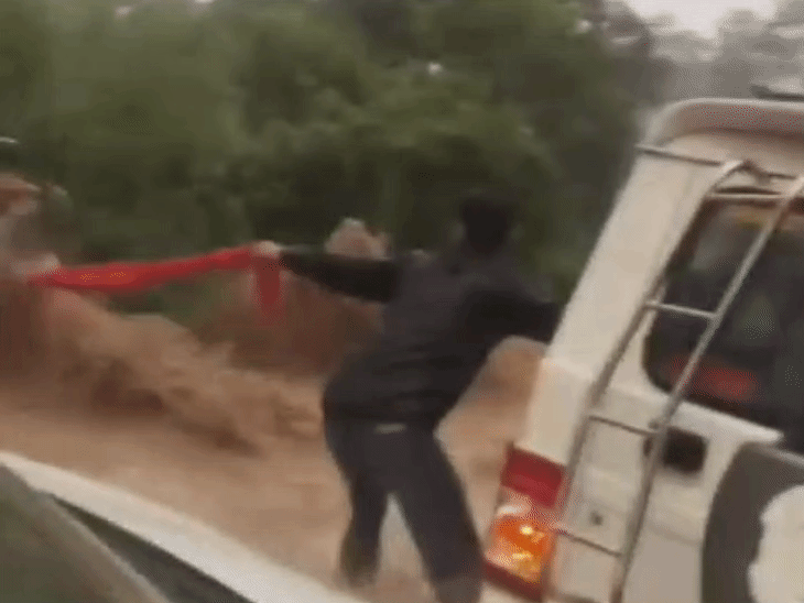 Bike rider trapped in the fast-flowing water, holding on tightly to the scarf.