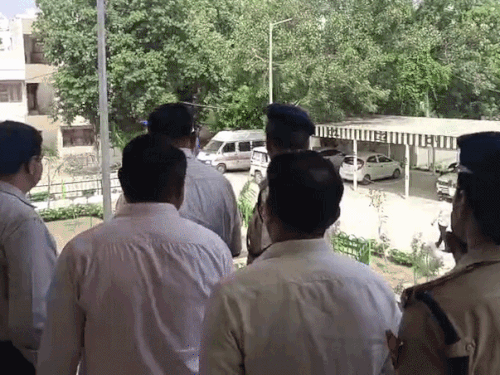 क्वार्टर की छत से खड़े होकर निरिक्षण करते हुए पुलिस अधिकारी।