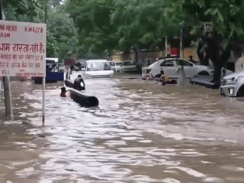 गुरुग्राम में झमाझम बारिश के बाद सेक्टर-22 बी में सड़क पर जलभराव में स्विमिंग करते बच्चे और पानी से निकलती कार।