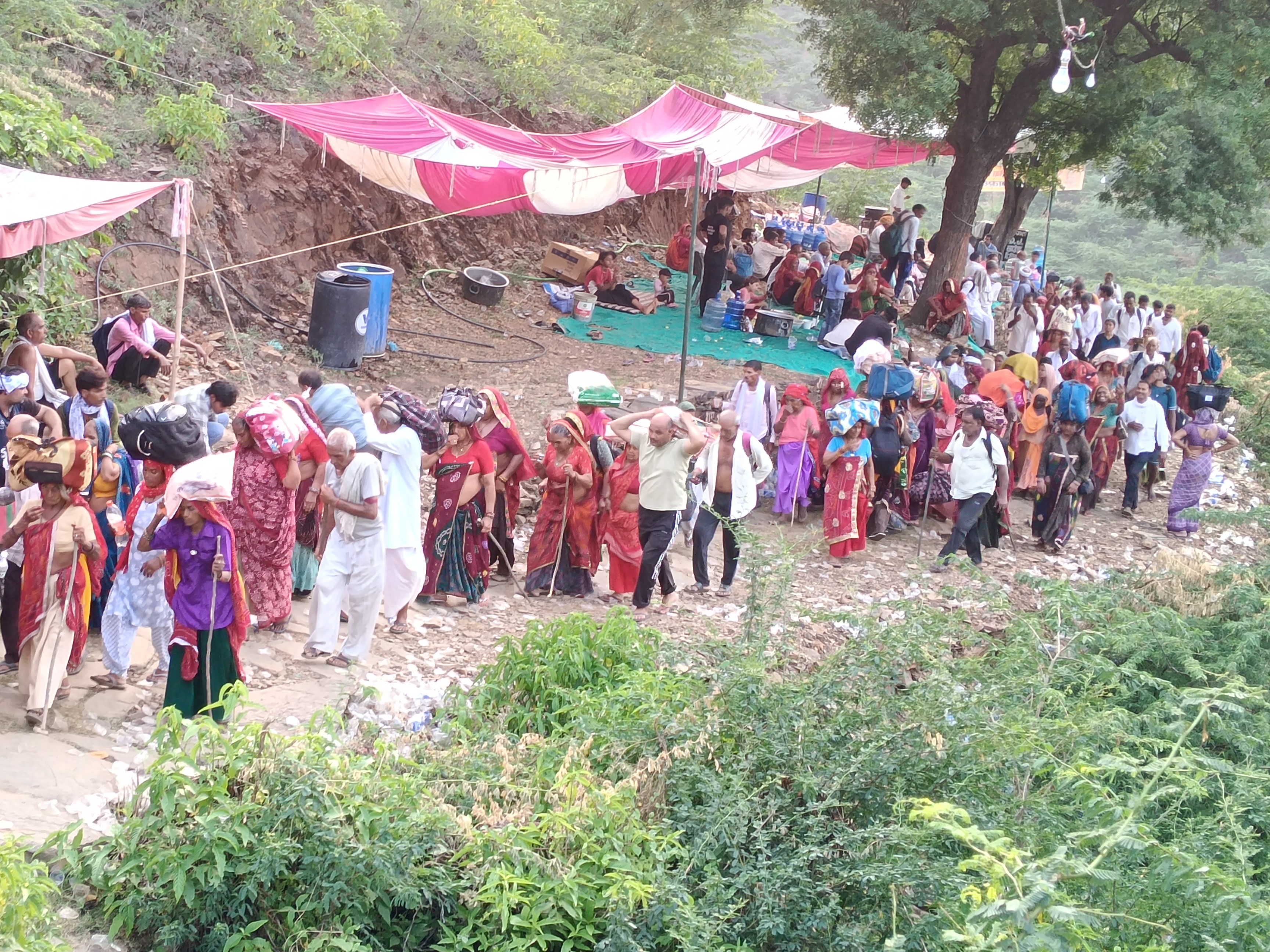 बुजुर्ग श्रद्धालु सिर पर थैला रखकर पहाड़ों के मुश्किल रास्तों से आगे बढ़े।