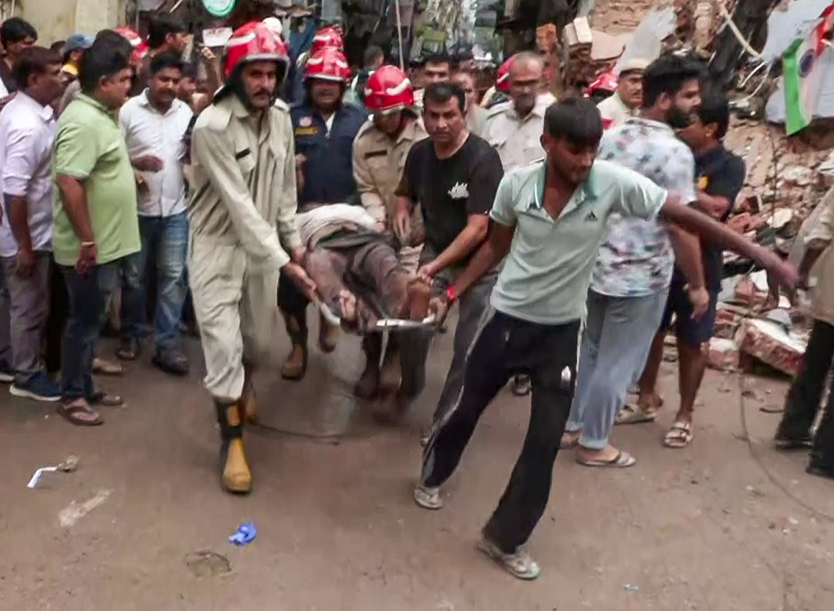 People and the rescue team carrying a youth pulled out from the debris towards an ambulance.