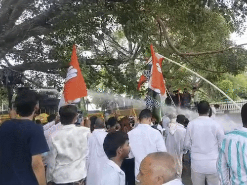 पानी की बौछारें होने के बाद झंडा उठाकर कार्यकर्ताओं ने प्रदर्शन किया।