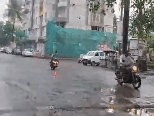 The picture shows a road in the Kalyan West area, where rainwater has collected in potholes.