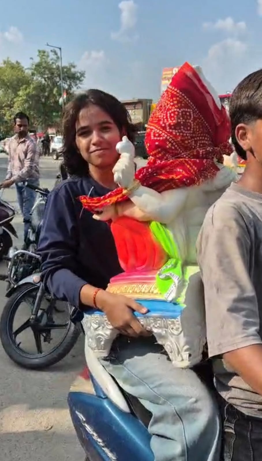 गणेश की मूर्ति खरीदकर ले जाती युवती।