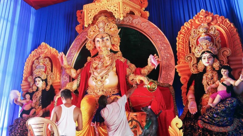 अगरतला के एक कम्युनिटी पंडाल में कारीगर भगवान गणेश की मूर्ति को अंतिम रूप देते हुए।
