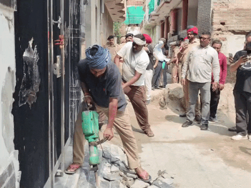 तस्करी के आरोपी के घर का अवैध हिस्सा तोड़ते निगम कर्मी।