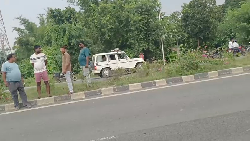 घटनास्थल पर पुलिस की गाड़ी और जुटे स्थानीय लोग।