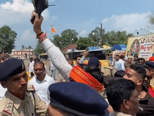 हाथ में चप्पल लेकर लहराते कार्यकर्ता।