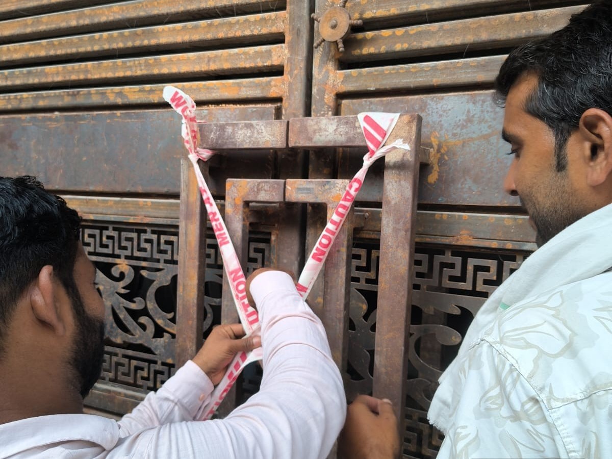 मकान को सील करते नगर निगम के अधिकारी।
