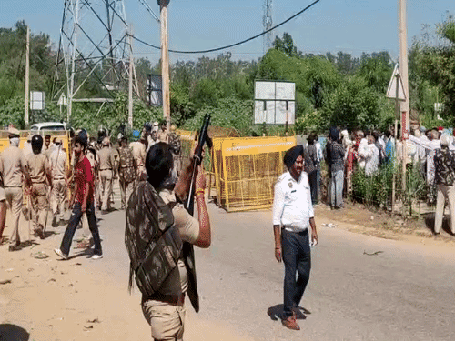 किसानों की तरफ आंसू गैस के गोले दागता पुलिसकर्मी।